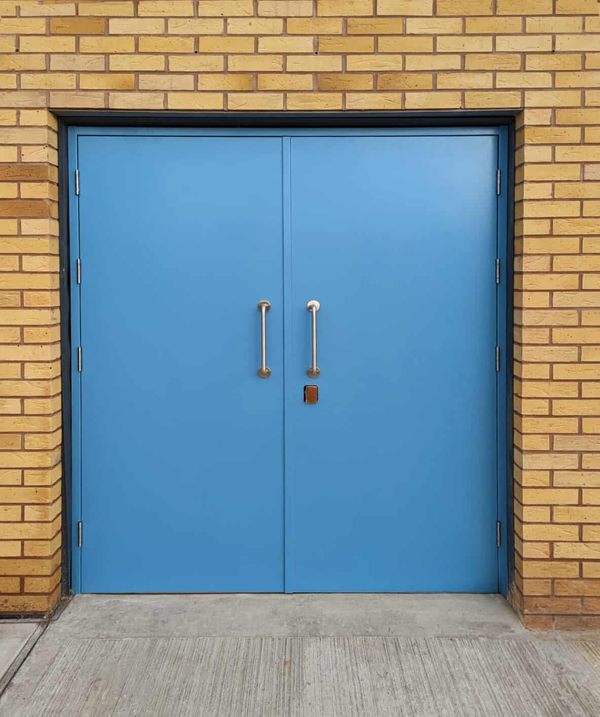 Blue double doors set in yellow brick wall