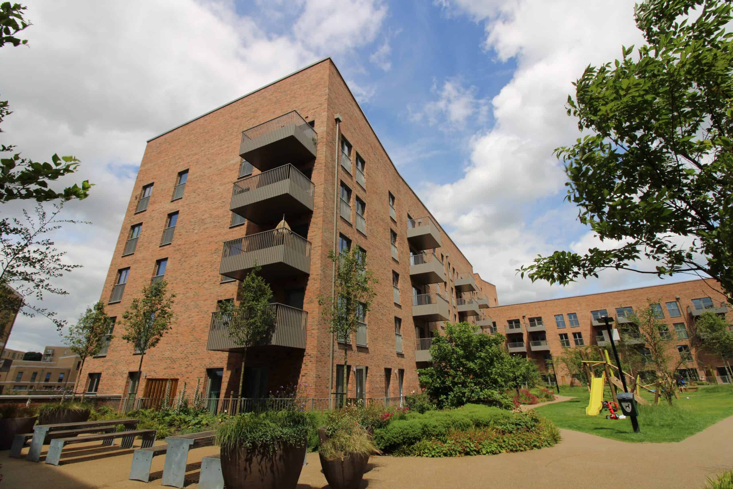 Modern brick apartment building with landscaped communal garden