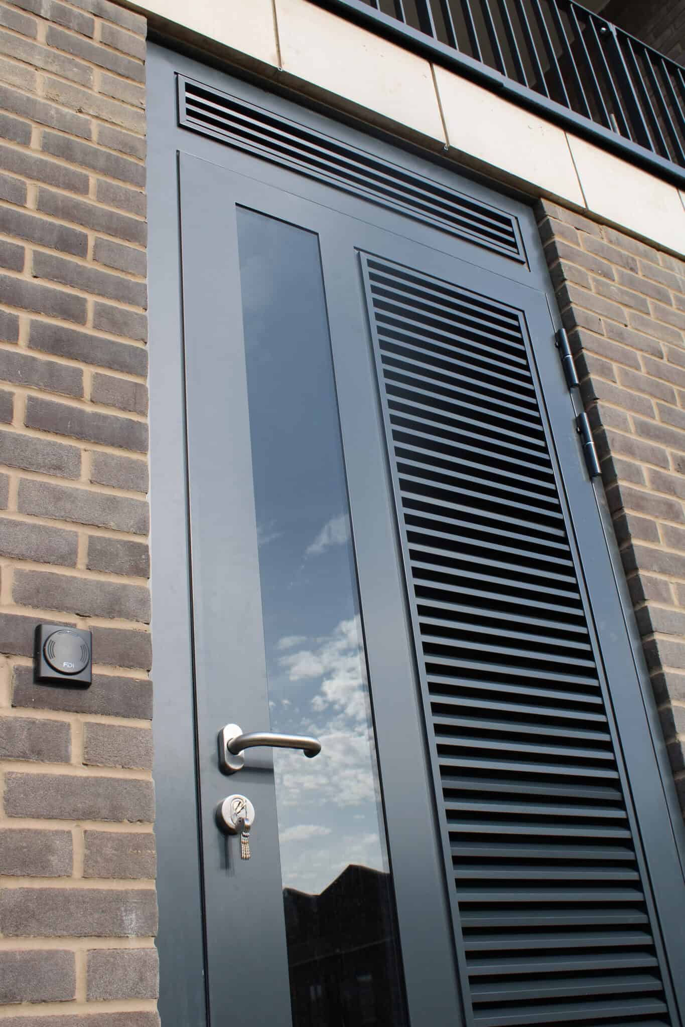 Modern grey metal security door with ventilation grille